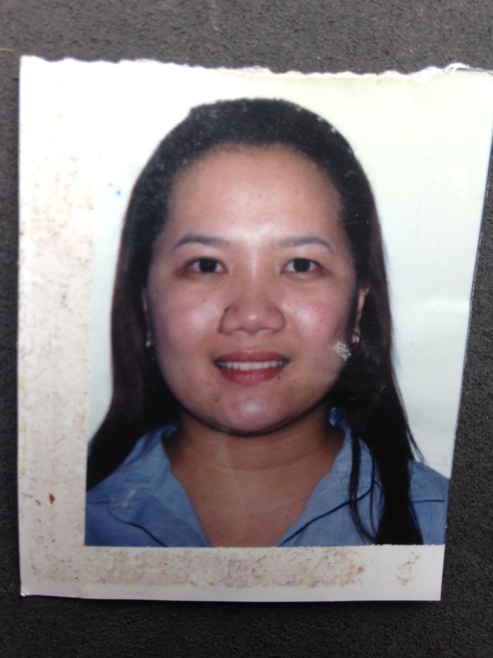 A passport photo of a woman with long black hair wearing a blue shirt.